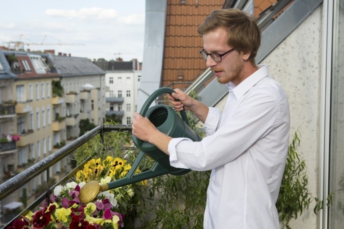 balkon bepflanzen lavendel junger mann giesst 