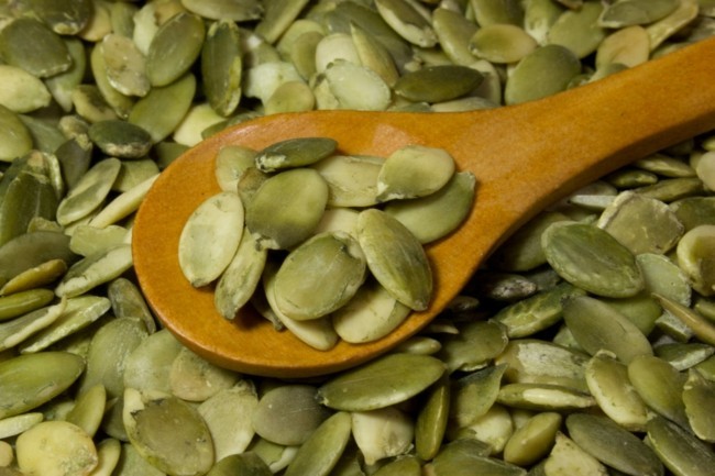 Pumpkin seeds and wooden spoon as background