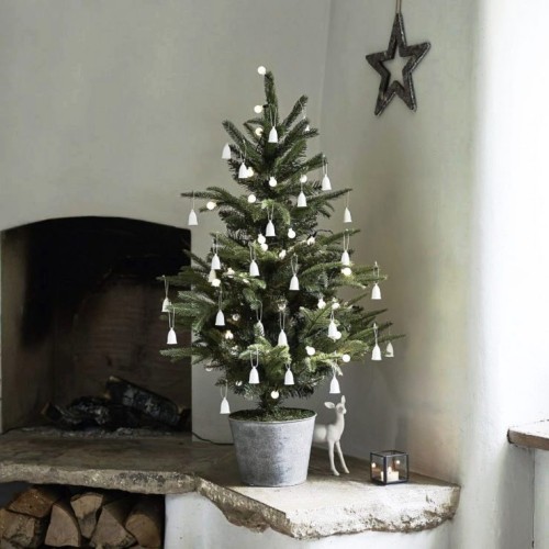 Weihnachtsbaum im Topf neben dem fenster mit geringer deko