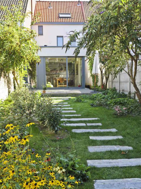 Garten gestalten Haus Hinterhof Steinplatten Rasen viele Blumen schöner Platz im Freien