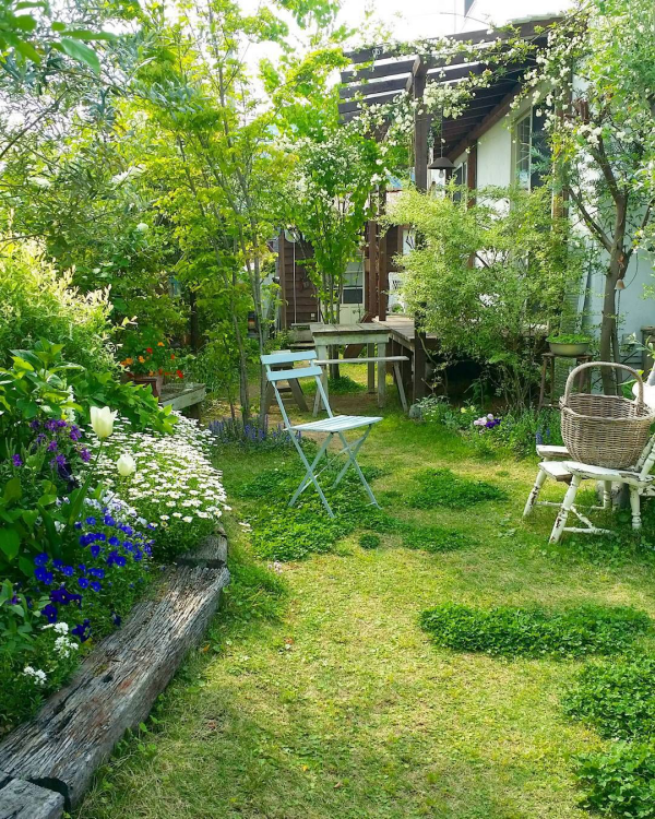 Garten gestalten Naturgarten Stuhl Korb viel Grün Blumen Rasen Sträucher Bäume erstklassiger Relax im Freien