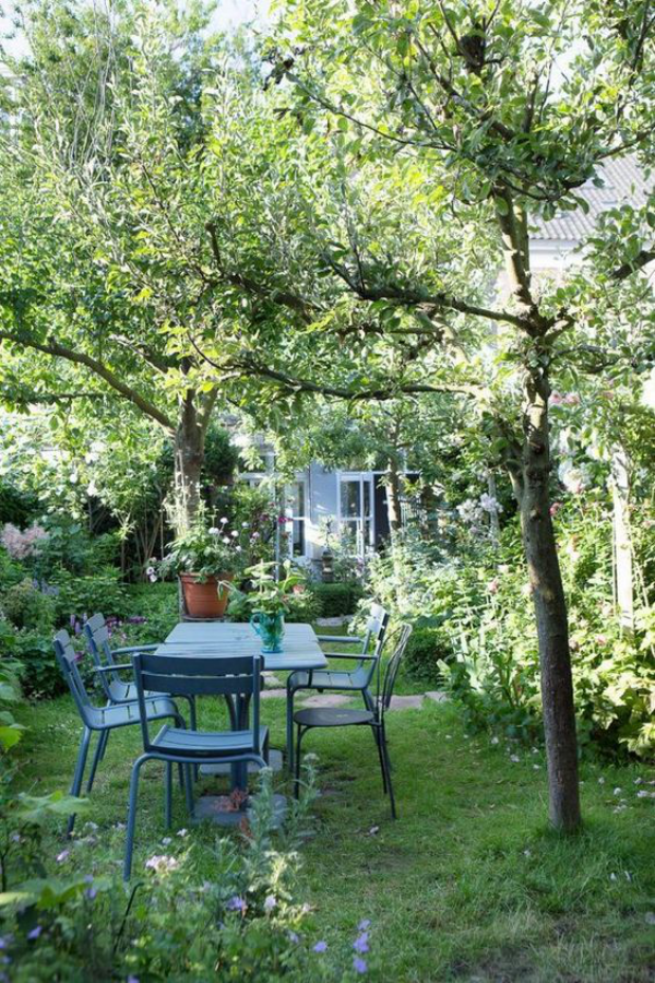 Garten gestalten Naturgarten viel Grün Pflanzen Sträucher Bäume Esstisch Stühle im Freien