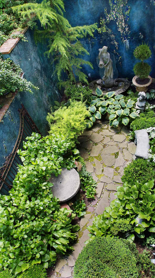 Garten gestalten kleiner Hinterhof schmaler Platz Steinfigur Steinplatten üppiges Grün