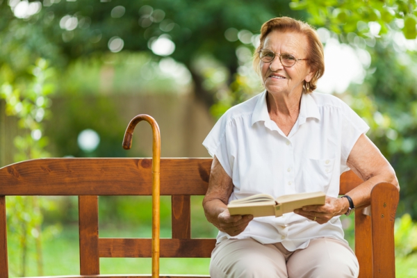 Elderly woman sitting and relaxing on a bench in park