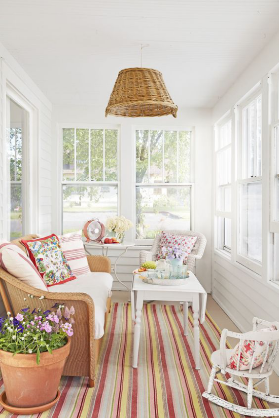 verglaste Veranda Glasveranda Plattform der Entspannung simple Einrichtung Sofa Sessel Deko Kissen gestreifter Teppich Topf mit Blumen Hängelampe Korb