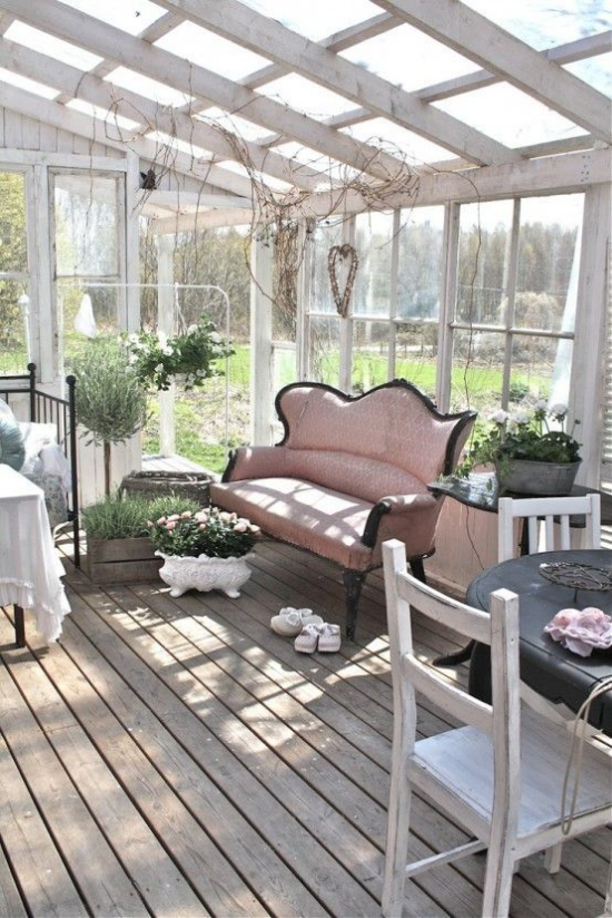 verglaste Veranda Glasveranda bequemes Sofa viele grüne Topfpflanzen verteilt im Raum