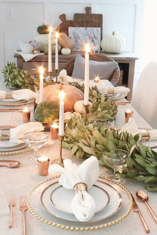 Herbstliche Tischdeko mit Kürbissen festlich gedeckter Tisch weiße Kerzen grüne Blätter schönes Besteck viel Glanz