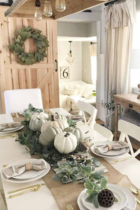 Herbstliche Tischdeko mit Kürbissen rustikale Atmosphäre weiße Kürbisse grüne Blätter