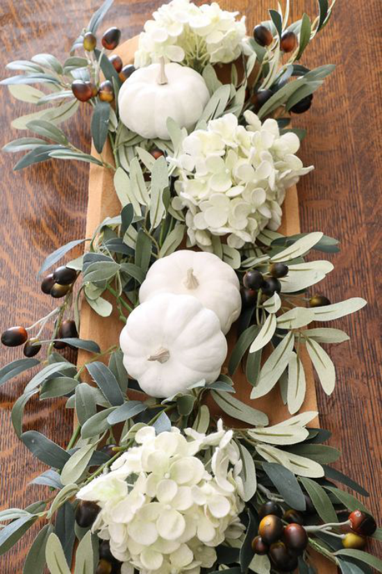 Herbstliche Tischdeko mit Kürbissen weiße Zierkürbisse auf Tablett aus Holz Hortensien grüne Blätter Eicheln