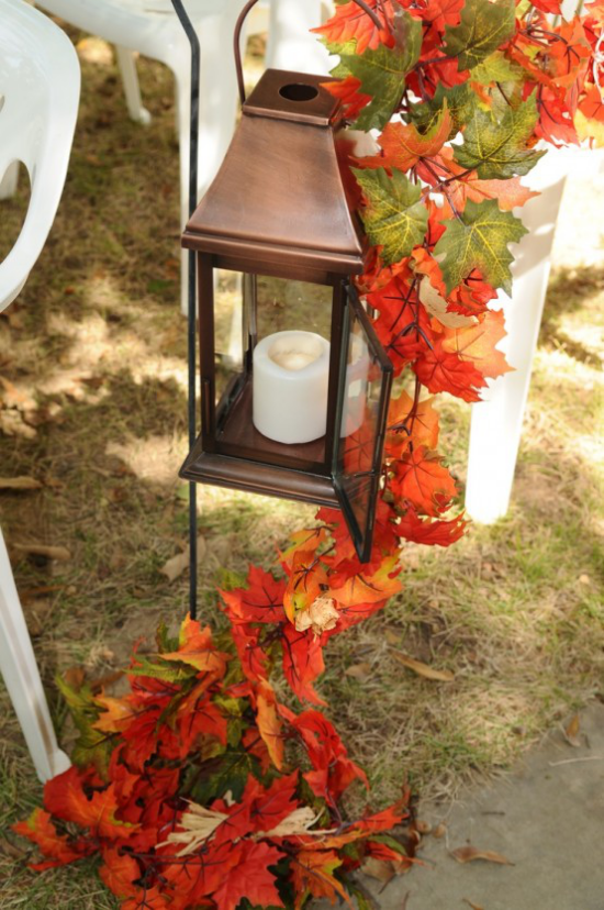 Laternen in der Herbstdeko eine Laterne im Garten geschmückt mit Kette aus buntgefärbten Herbstblättern