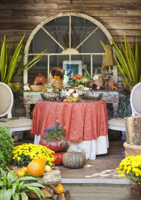 Herbstdeko für draußen buntes Arrangement gesättigte Farben Chrysanthemen in Töpfen Kürbisse alter runder Tisch orangenfarbene Tischdecke Stuhl