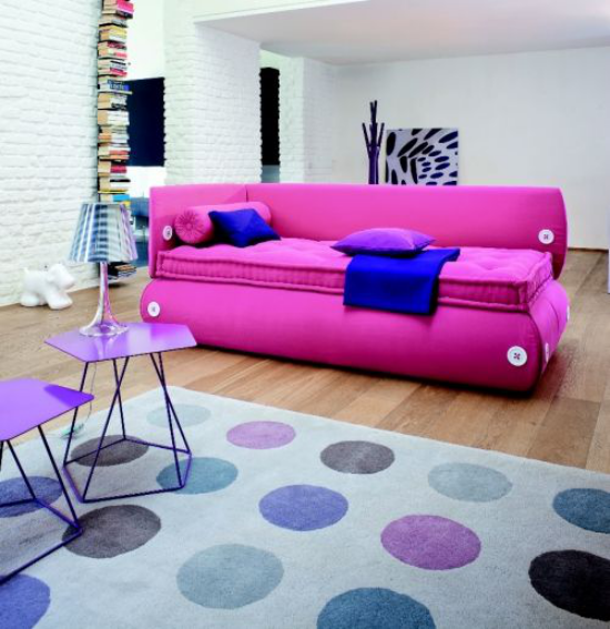 extravagante Sofas ausgefallenes Modell in Pink marineblaue Wurfdecke Teppich Tisch Lampe rücken in den Hintergrund