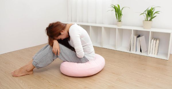 PMS Symptome Sitzen am Kissen auf dem Boden