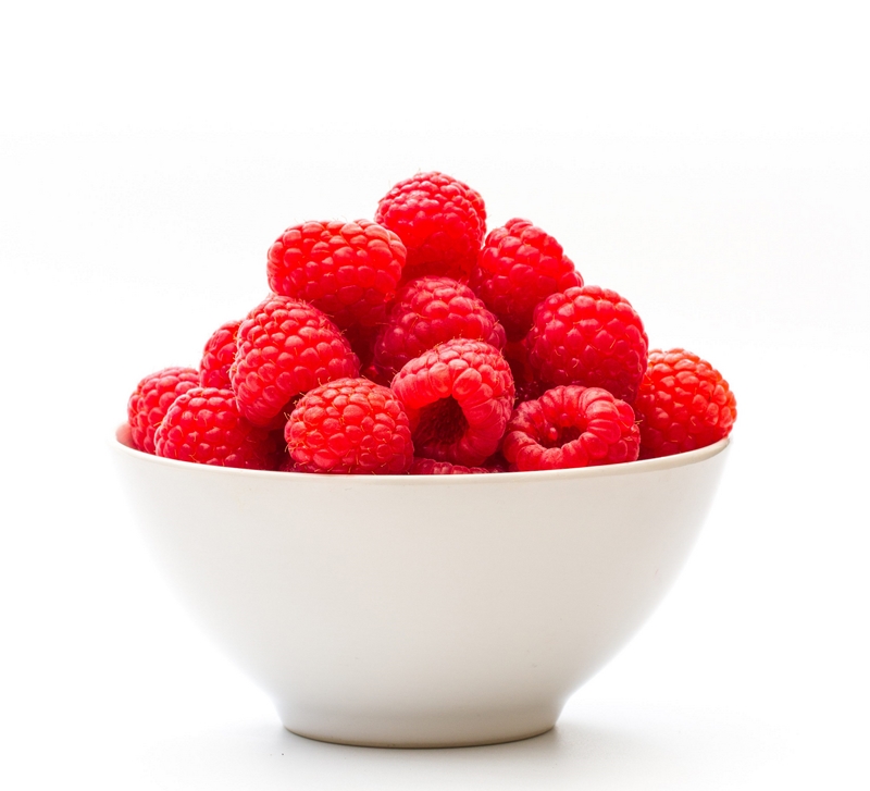 Close-Up Of Raspberries In Bowl Against White Background