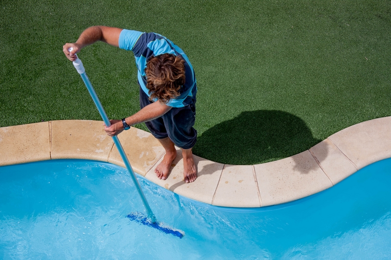 Male pool cleaner cleaning a blue pool