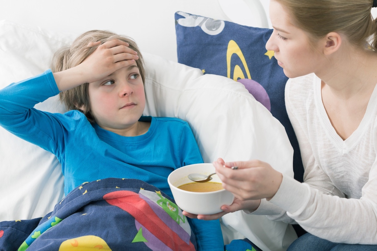 Kind mit Fieber und seine Mutter - warme Suppe im Bett essen